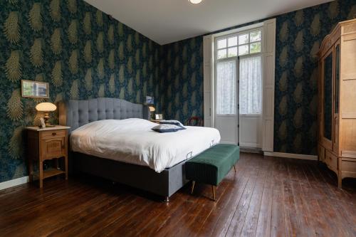 een slaapkamer met een bed, een tafel en een raam bij Villa les Bruyères in Dilsen-Stokkem