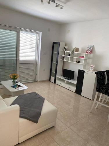 a living room with a white couch and a television at Apartments MaRo in Pag