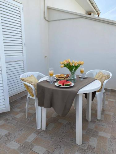 a table with a plate of food and flowers on it at Apartments MaRo in Pag