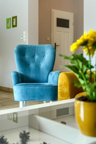 a blue chair in a living room with a plant at Rentynówka in Gietrzwałd