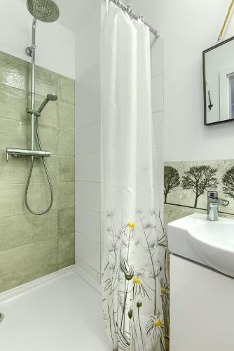 a bathroom with a shower curtain with flowers on it at Rentynówka in Gietrzwałd