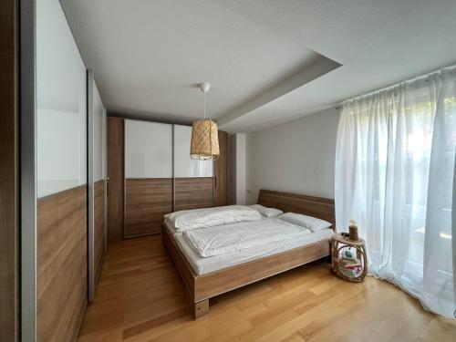 een slaapkamer met een bed en een groot raam bij Lo Ferienwohnung in Friedrichshafen