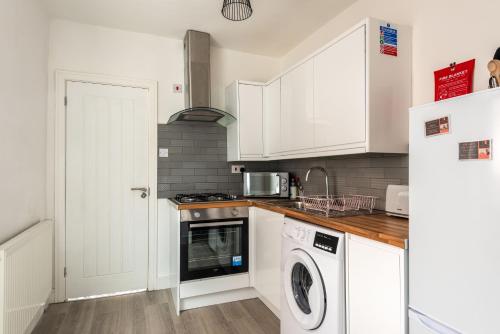 cocina con armarios blancos, lavadora y secadora en Hopetown Apartment-modern 1 bed with free parking, en Normanton