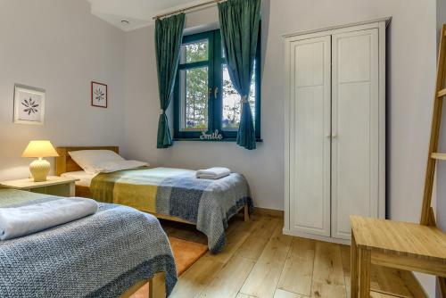 a bedroom with two beds and a window at Rentynówka in Gietrzwałd
