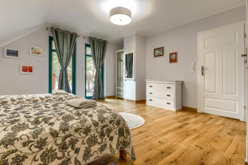 a bedroom with a bed and a wooden floor at Rentynówka in Gietrzwałd