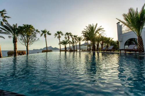 una piscina con palmeras y un edificio en ELYSIUM GARDEN HOTEL, en Bozyazı