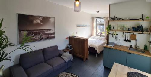 een woonkamer met een bank en een slaapkamer bij Studio tussen de bossen en de bollenvelden in Noordwijkerhout