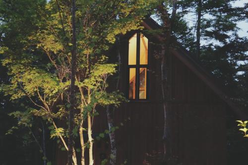 a window on the side of a cabin in the trees at Karuizawa Forest Seasons Villa in Karuizawa