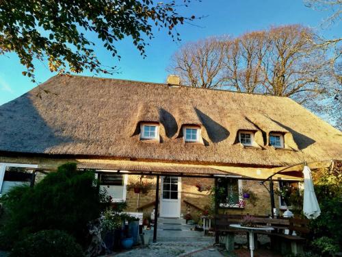 an old house with a thatched roof with a table at Kreatives Wohnen unter Reet ruhig und doch zentral in Schwabstedt