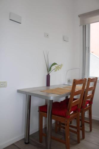 a dining room table with two chairs and a potted plant at Zimmer Ba'Ir in Kefar Sava