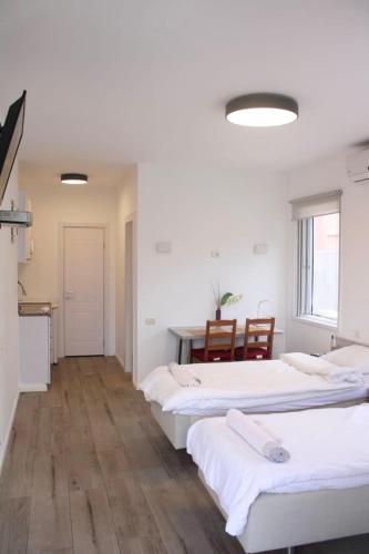 two beds in a room with a table and chairs at Zimmer Ba'Ir in Kefar Sava
