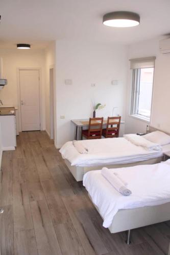 three beds in a room with a table and chairs at Zimmer Ba'Ir in Kefar Sava