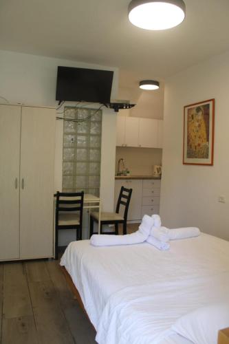 a bedroom with two beds and a kitchen with a table at Zimmer Ba'Ir in Kefar Sava
