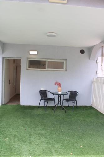 a table and chairs in a room with green grass at Zimmer Ba'Ir in Kefar Sava