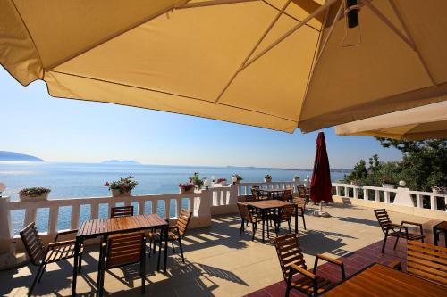 a patio with tables and chairs and an umbrella at Seascape Villas in Vlorë