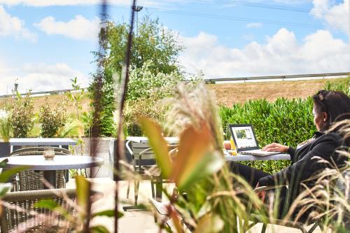 a man sitting at a table with a laptop at Kyriad Paris Sud Les Ulis Courtaboeuf in Les Ulis
