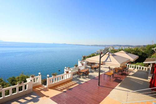 a balcony with tables and chairs next to the water at Seascape Villas in Vlorë