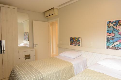 - une chambre avec 2 lits et un miroir dans l'établissement Apt Jurerê, à Florianópolis