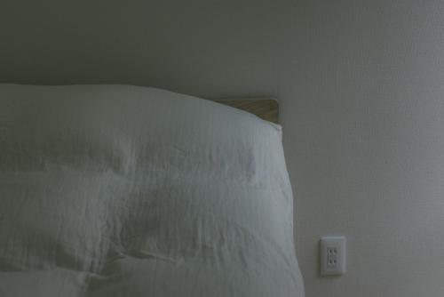 a white bed with a white pillow and an electrical outlet at Karuizawa Forest Seasons Villa in Karuizawa