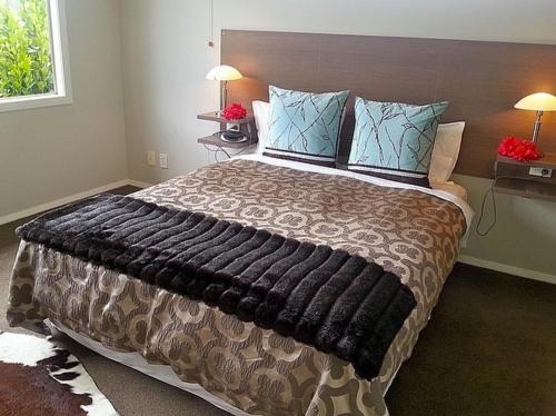 Un dormitorio con una cama grande con una manta grande en Mistry Hideout - Lakes Resort Pauanui Home, en Pauanui