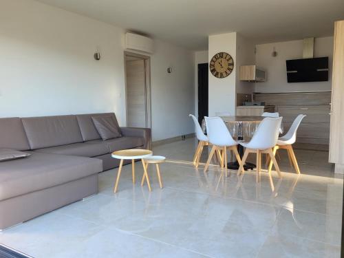 a living room with a couch and a table and chairs at Appartement neuf 3 chambres vue mer Propriano in Propriano