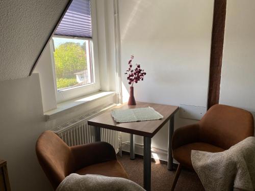Una pequeña mesa con dos sillas y un jarrón con flores. en Haus Mohnke en Hiddensee