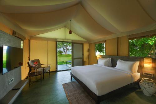 a bedroom with a large bed and a large window at Fireflies Kabini in Begūr