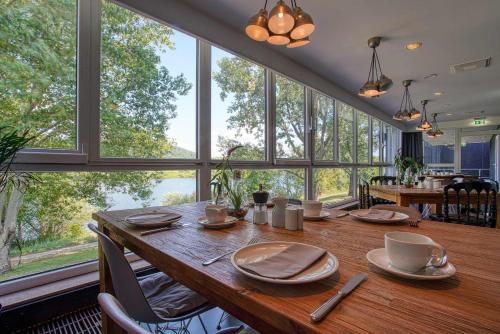 a dining room with a wooden table and large windows at FourSide Plaza Hotel Trier, Trademark Collection by Wyndham in Trier