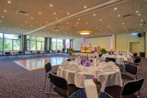 a banquet hall with tables and chairs and a stage at FourSide Plaza Hotel Trier, Trademark Collection by Wyndham in Trier