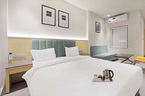 una camera con un grande letto bianco e una sedia di FabHotel Oasis Yellow Courtyard a Bhopal