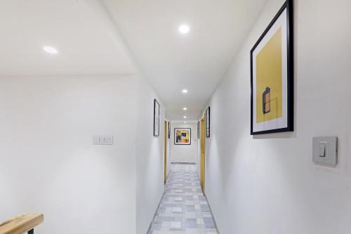 a hallway with white walls and paintings on the walls at FabHotel Yellow Courtyard in Bhopal