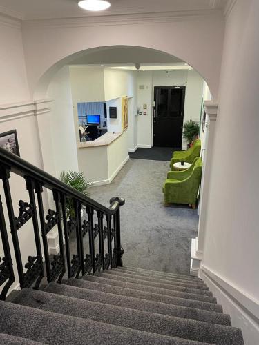 a living room with a staircase and a green couch at Dusties Hotel in Rotherham