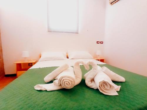 dois cisnes feitos de toalhas numa cama em Ai Normanni em Palermo