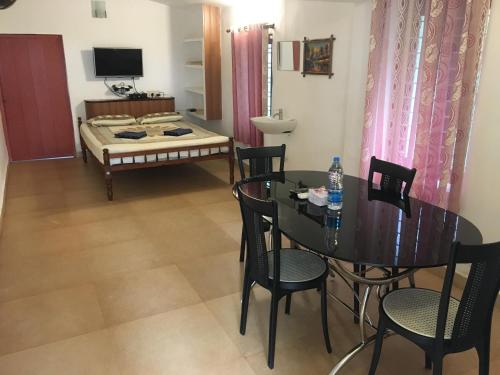 a dining room with a table and chairs and a bed at Cherai Beach Retreat in Cherai Beach