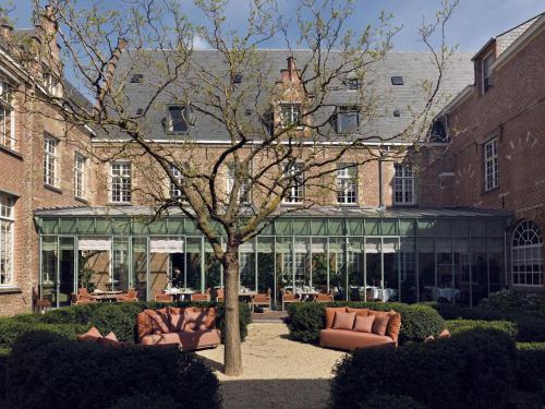 a building with a tree in the middle of a courtyard at Botanic Sanctuary Antwerp - The Leading Hotels of the World in Antwerp