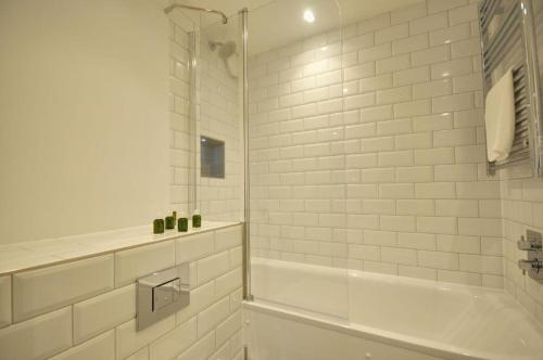ein weißes Bad mit einer Badewanne und einer Dusche in der Unterkunft The Square Bournemouth in Bournemouth