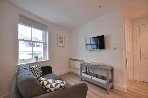 ein Wohnzimmer mit einem Sofa und einem TV in der Unterkunft The Square Bournemouth in Bournemouth