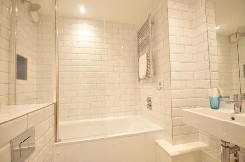 ein weißes Badezimmer mit einer Badewanne und einem Waschbecken in der Unterkunft The Square Bournemouth in Bournemouth