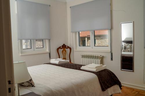 a bedroom with two beds and two windows at Casa Origens in Seia