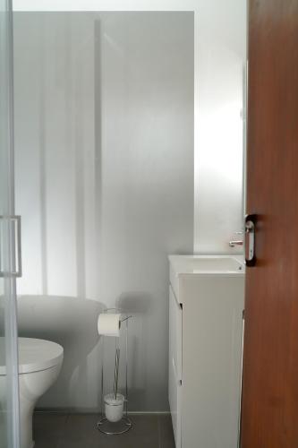 a white bathroom with a toilet and a sink at Casa Origens in Seia