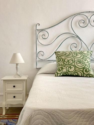un letto con cuscino verde e comodino con lampada di Casa Chiara a Città di Lipari