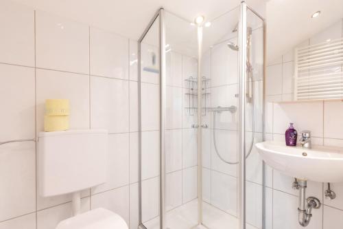 a white bathroom with a shower and a sink at Haus Bergblick in Fuschl am See