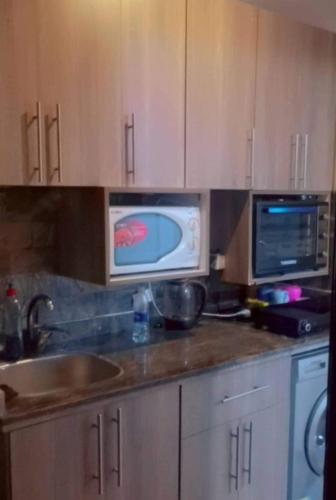 a kitchen with a sink and a microwave at استديو راقي ارضي بجنينة للعائلات فقط in El Alamein
