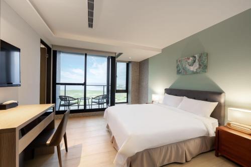 Habitación de hotel con cama, escritorio y TV. en 拾滬海景會館 澎湖海景民宿, en Kuang-yang