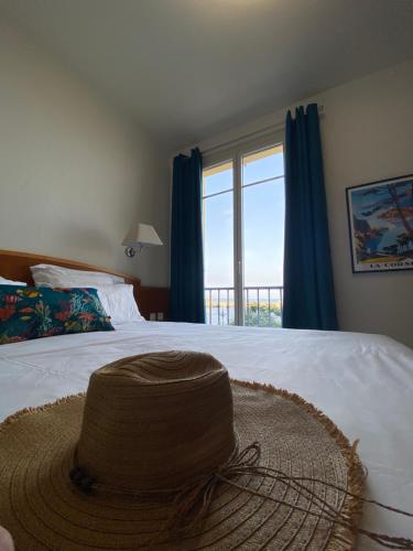 a hat sitting on top of a bed with a window at Hôtel Posta Vecchia in Bastia