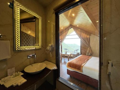 a bathroom with a sink and a bed and a mirror at Kufri Pacific Resort in Mundaghat 