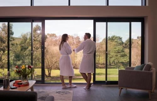 Ein Mann und eine Frau stehen vor einem Fenster in der Unterkunft Old Thorns Hotel & Resort in Liphook