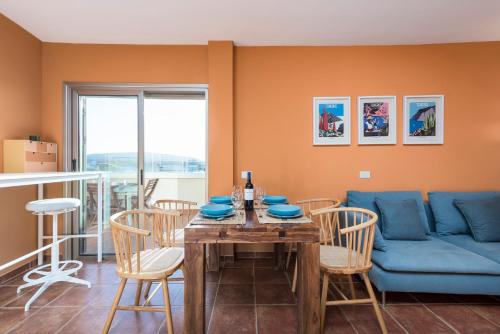jadalnia ze stołem i niebieską kanapą w obiekcie MEDANO4YOU The Penthouse La Jaquita w mieście El Médano