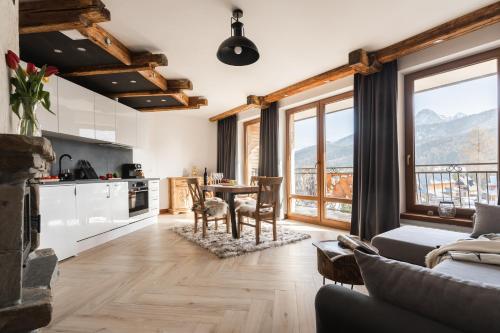 a kitchen and living room with a table and chairs at Aparthotel Delta Royal in Kościelisko