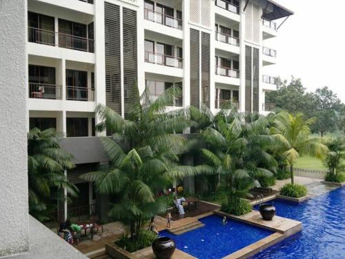 a large building with a swimming pool and palm trees at Garden View Pulai Springs Resort in Skudai